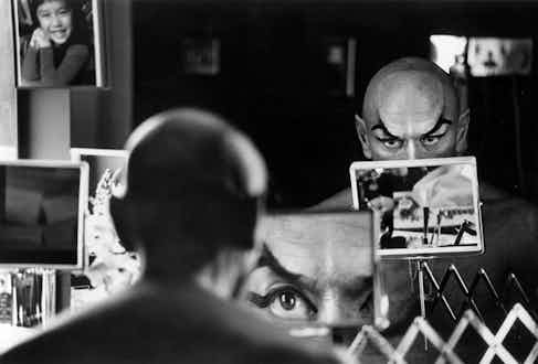 Yul Brynner does a double check on his make-up with a magnifying mirror.
