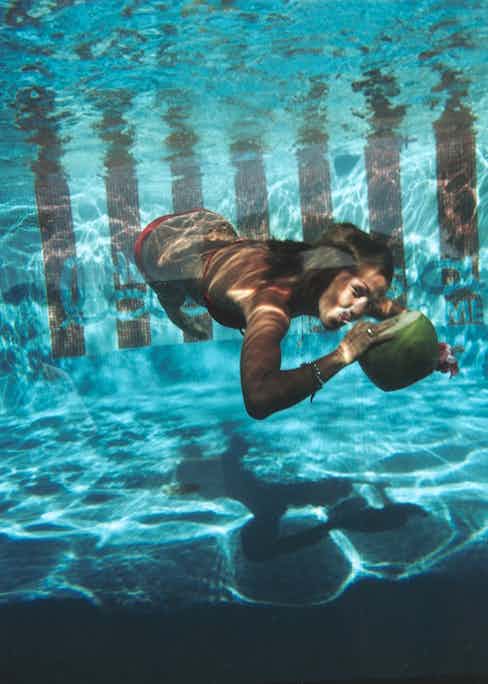 A woman drinking from a coconut underwater in the pool at Las Brisas Hotel in Acapulco, Mexico, February 1972 (Photograph by Slim Aarons)