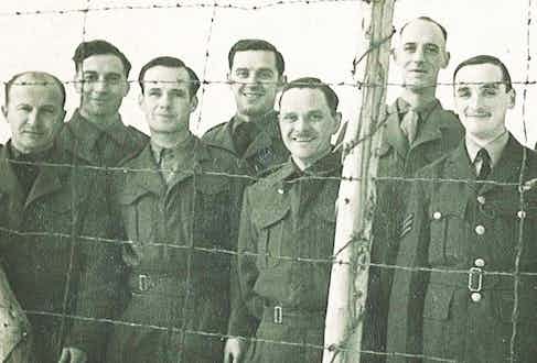 Gerald Imeson behind barbed wire at Stalag Luft III (centre back).