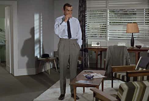 Sean Connery’s James Bond shows another way to wear wide trousers in Dr No, 1960. Although high-waisted and with twin pleats, the trousers taper gently down to a narrow opening, giving them more of a contemporary feel even today.