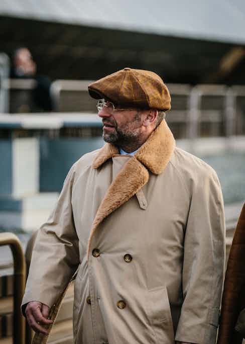 A gentleman in Florence wears a brown peaked cap with a large gold overcheck and tonal shearling coat. Photo by Jamie Ferguson.