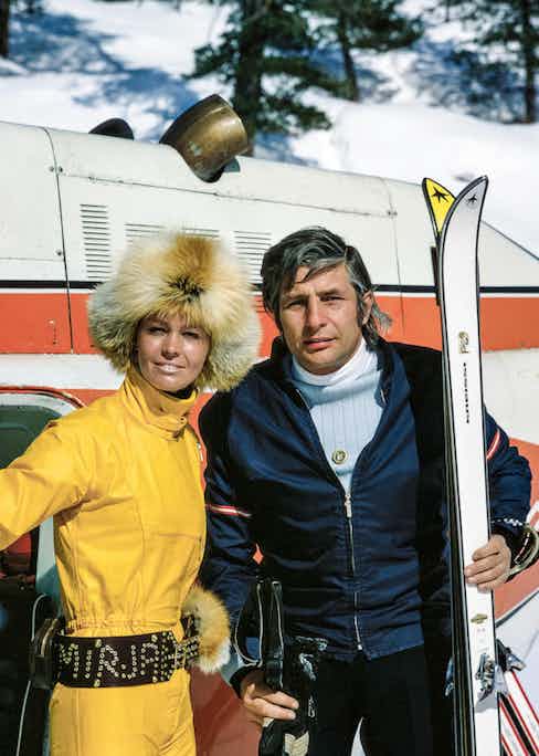 Gunter Sachs looks polished in a navy fitted ski jacket with a pale blue and white two-tone rollneck at the Swiss ski resort of St. Moritz with his wife Mirja Larsso, circa 1972.