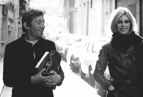 Simple and refined in a collarless jacket with a white round-neck shirt underneath, Gainsbourg walks with then-girlfriend Brigitte Bardot in Paris, 1960. Photograph by REPORTERS ASSOCIES/Gamma-Rapho via Getty Images.