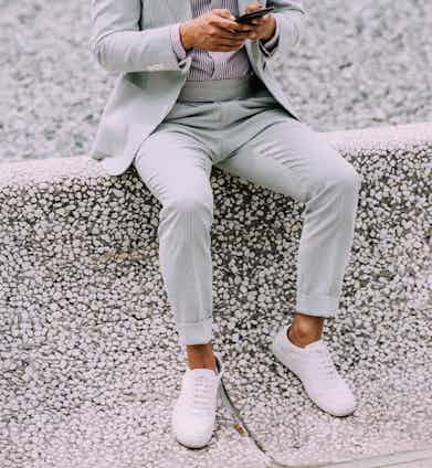 A pastel blue suit and striped shirt paired with minimalist white sneakers. A crisp white pocket square co-ordinates perfectly with the white trainers.