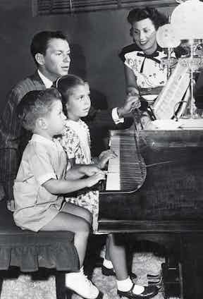 Frank Sinatra sits at the piano with his first wife, Nancy Barbato, and their children, Nancy and Frank Jr. (Photo by Hulton Archive/Getty Images)